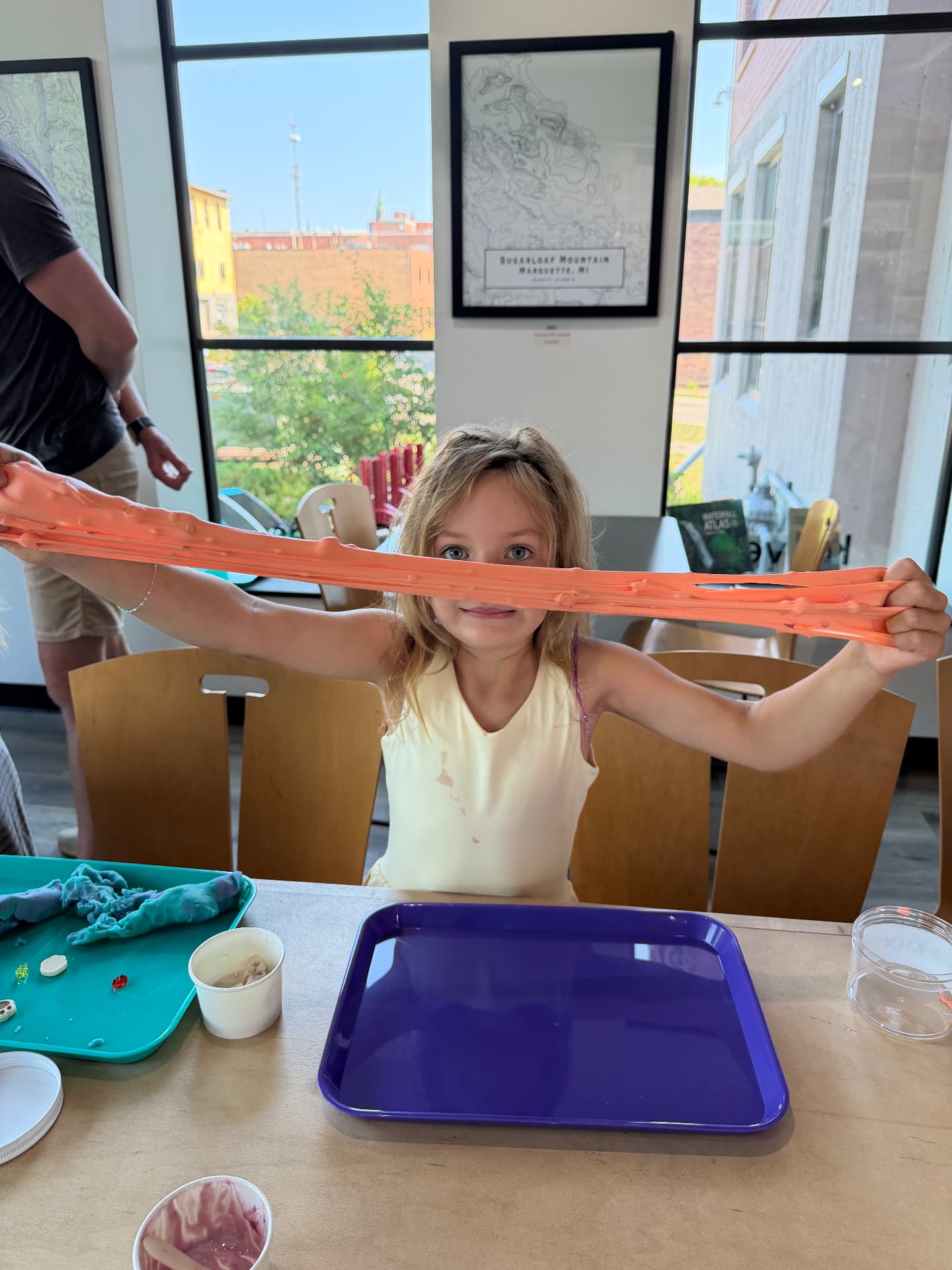 A girl stretching a long ribbon of orange slime between her hands