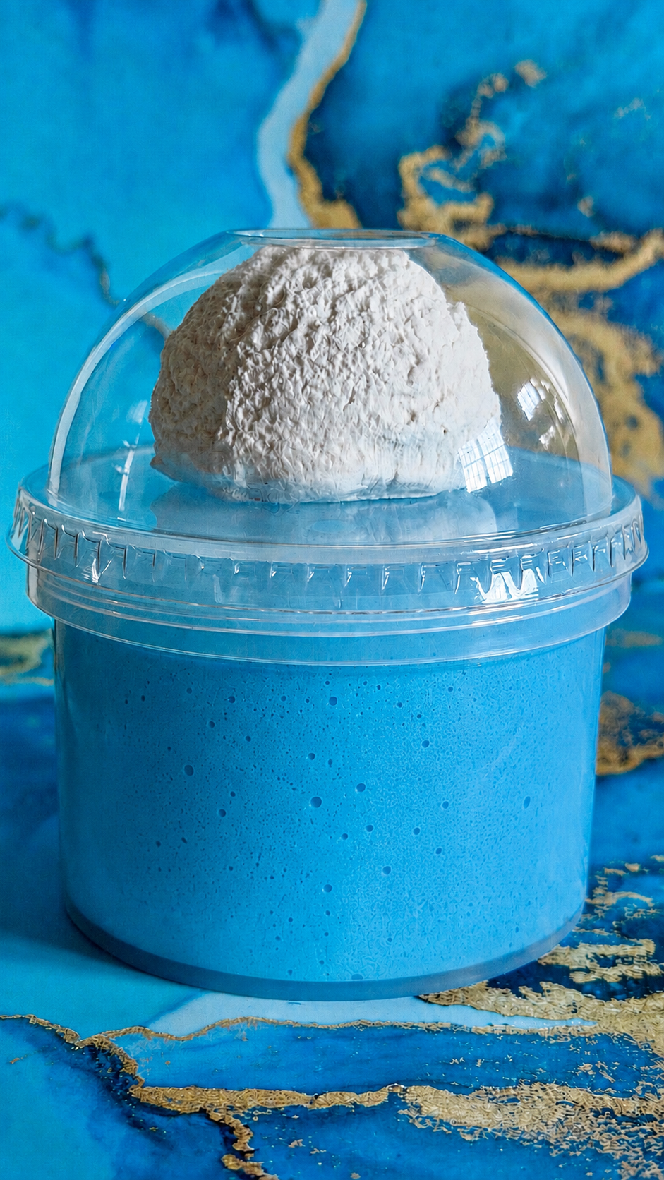 Blue and white swirled slime in a clear domed container